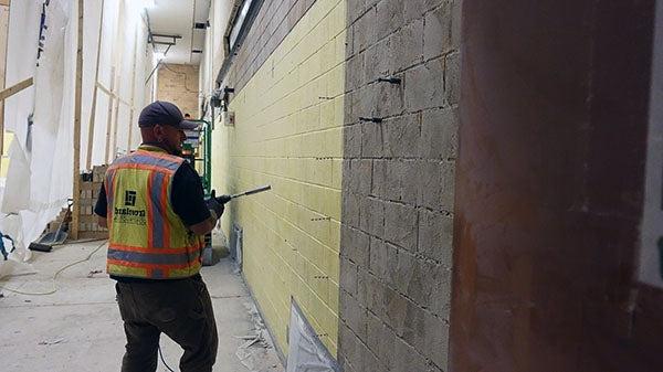 一名工人在正在施工的砖墙前拿着一把大钻