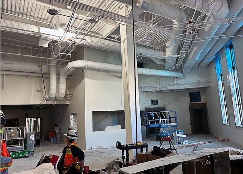 a two story interior space under construction with large pipes in the ceiling